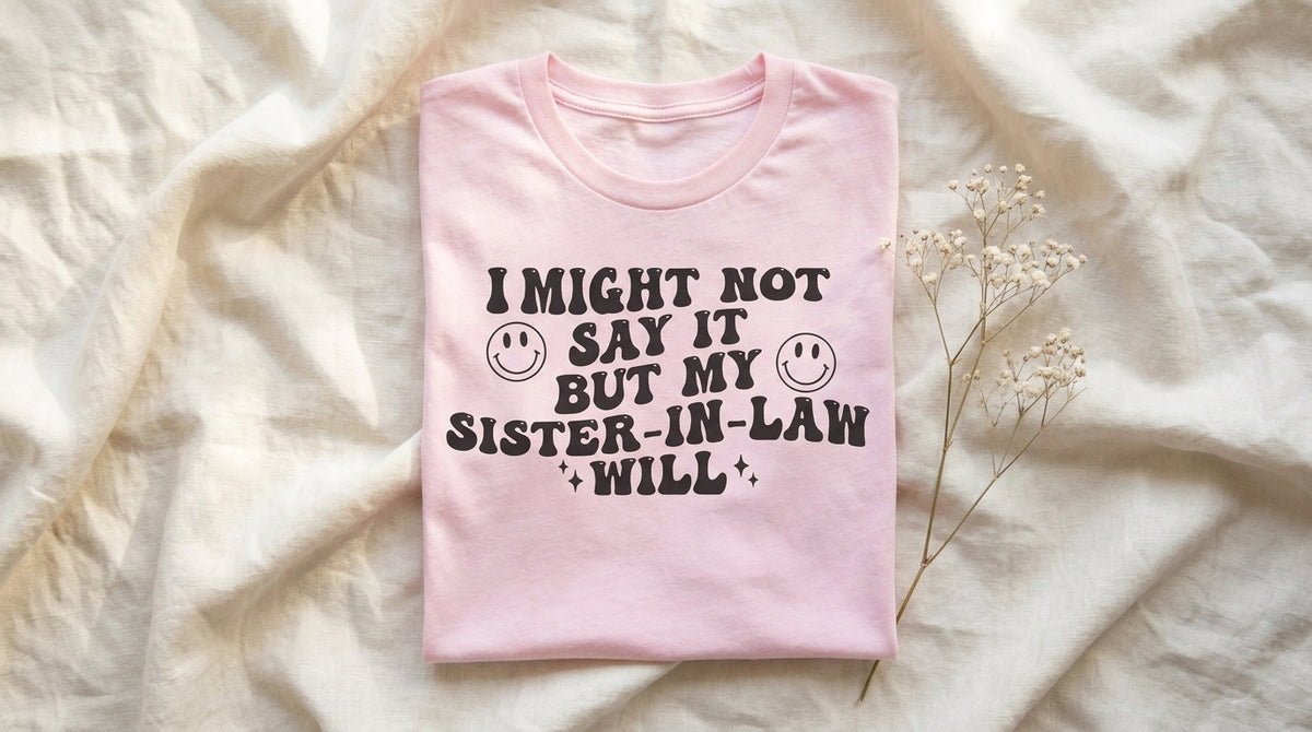 Pink I Might Not Say It But My Sister In Law Will tee folded on rumpled ivory linen with baby's breath sprig – Peachy Sunday sister in law gift guide