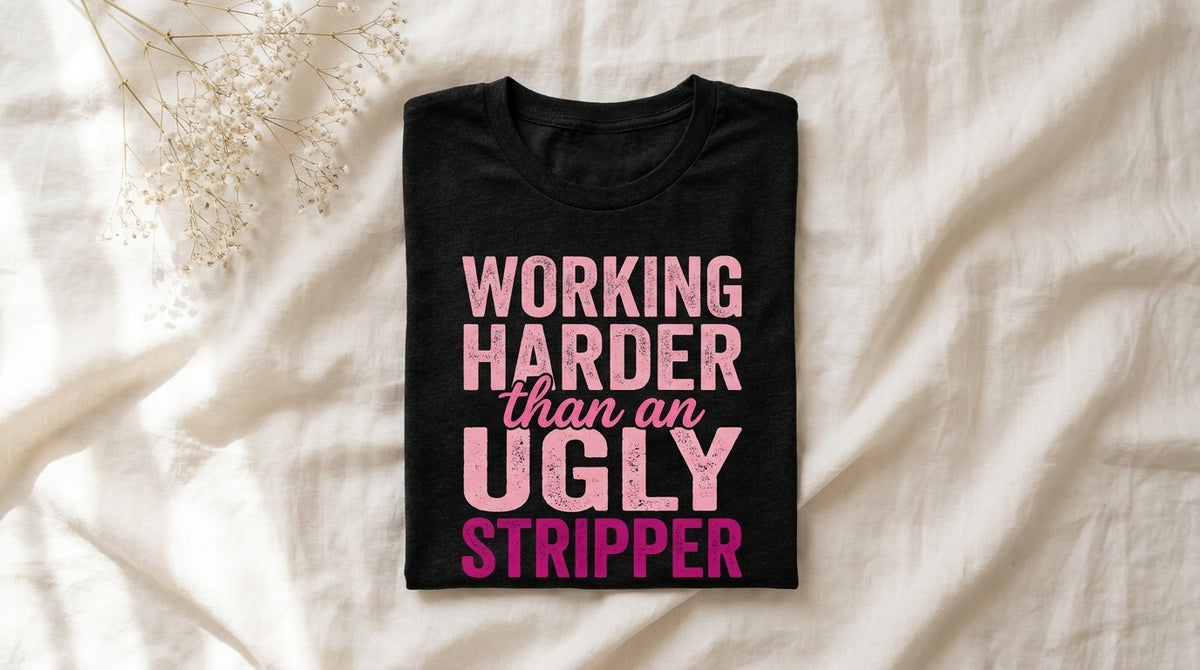 Folded black heather Working Harder Than An Ugly Stripper t-shirt on rumpled ivory linen with morning window light and baby's breath sprig – Peachy Sunday Journal work humor survival guide