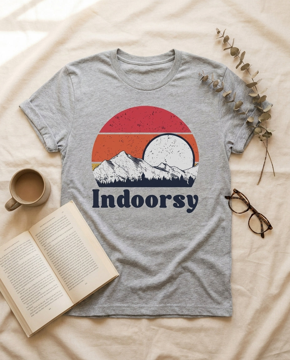 Athletic heather Indoorsy graphic tee flat-laid on cream linen with coffee, paperback, and glasses – Peachy Sunday UGC flat lay