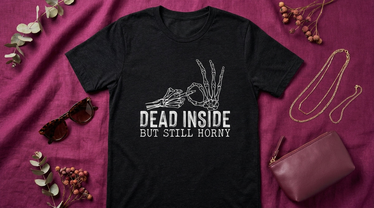 Dead Inside But Still Horny black heather graphic tee UGC flat lay on rich plum berry linen with sunglasses and gold jewelry – Peachy Sunday dark humor shirt