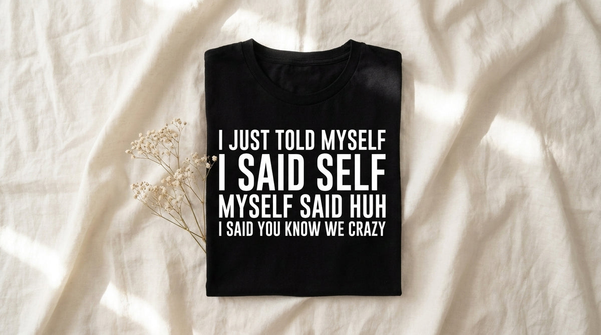 Folded black I Just Told Myself I Said Self tee on rumpled ivory linen with baby's breath sprig and morning window light – Peachy Sunday Journal internal monologue survival kit