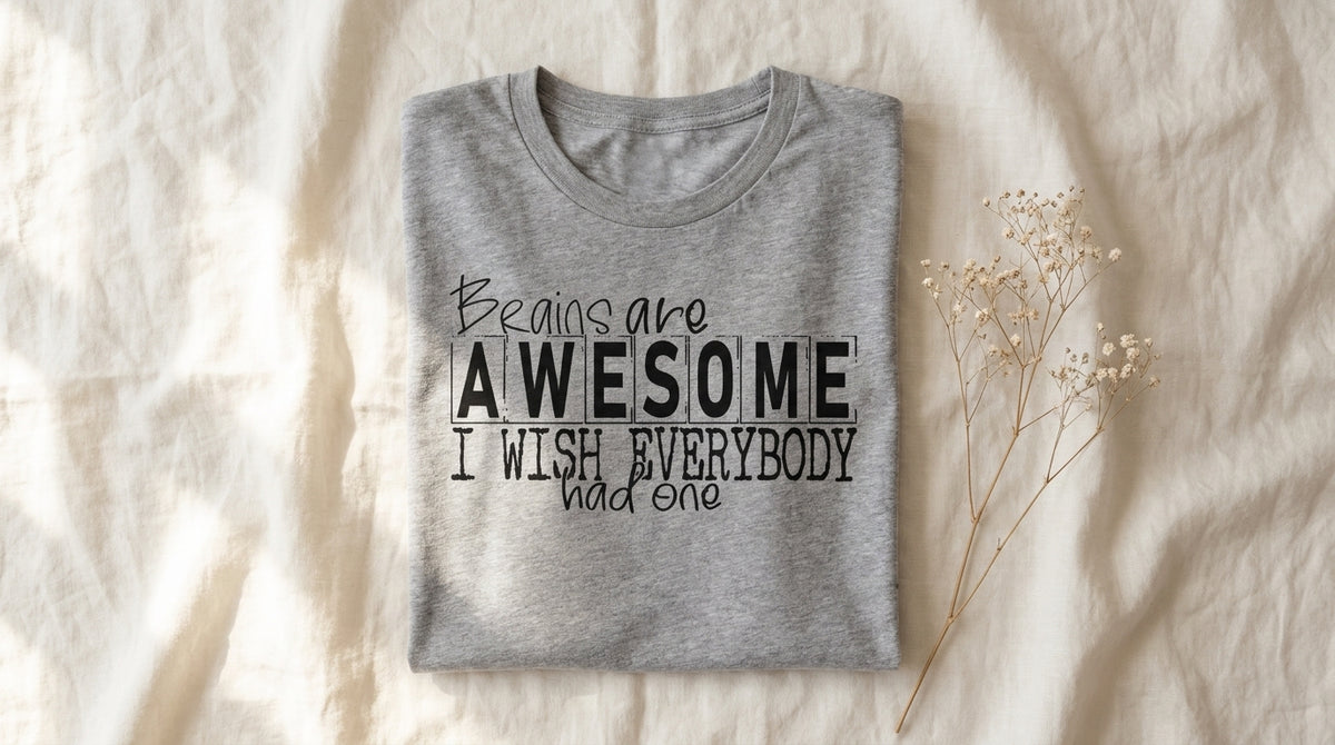 Brains Are Awesome graphic tee folded on rumpled ivory linen with window light and baby's breath sprig – Peachy Sunday Journal weekend reset lifestyle